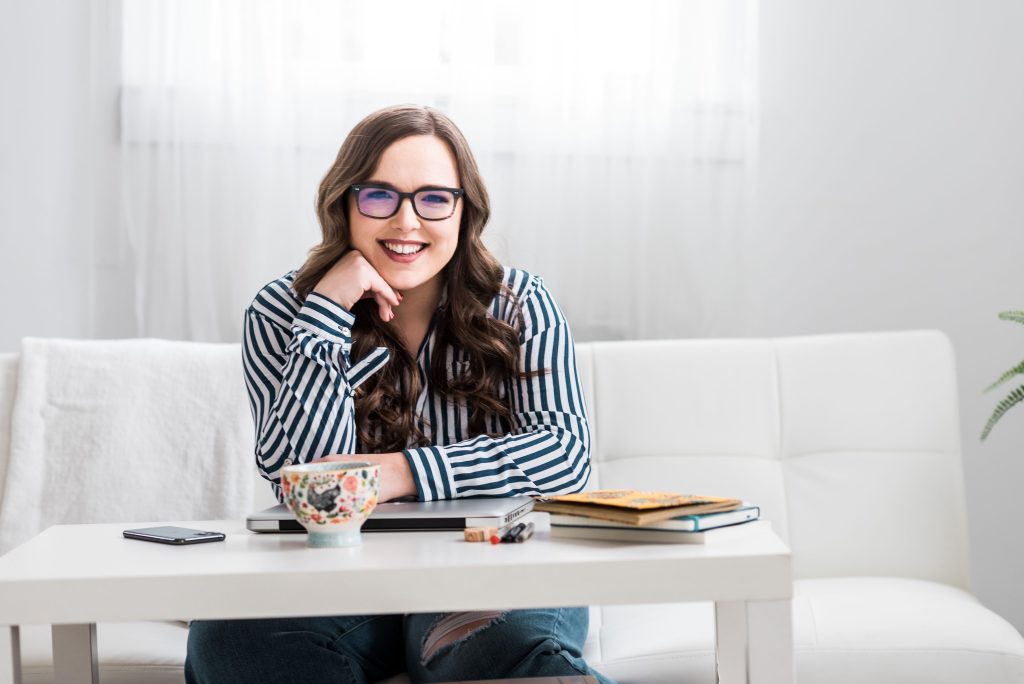 Cassie Christopher, Wellness Workshop Speaker, sits at a table smiling at the camera